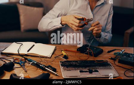 Making the necessary repairs. an unrecognizable female computer technician repairing a hard drive in her workshop. Stock Photo