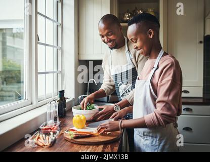 What you got over there. an affectionate young couple preparing dinner in their kitchen. Stock Photo
