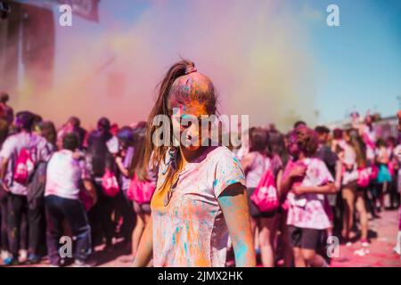 Young woman enjoying with holi color crowd Stock Photo