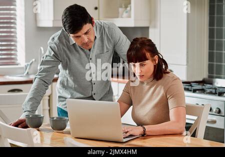 Let me see if I filled in all the fields. a woman using a laptop with her husband standing beside her. Stock Photo