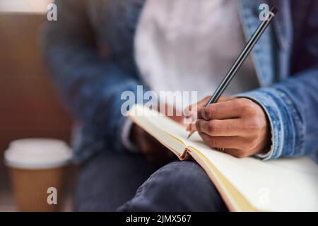 Its all in the notes. a young woman making notes while sitting outdoors. Stock Photo