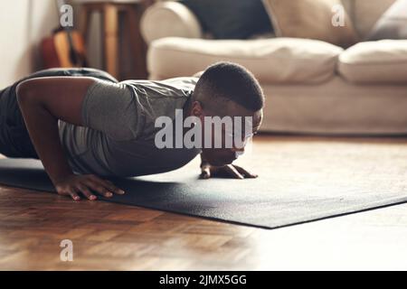 You have to be fearless in order to achieve results. a sporty young man doing push up exercises at home. Stock Photo