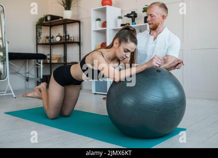 Female patient with physiotherapist doing exercises with ball Stock Photo