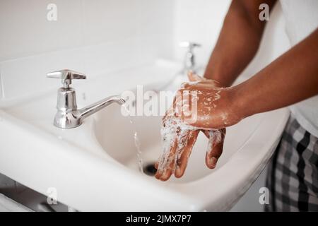 Always start with clean hands. an unrecognizable man washing his hands in the bathroom at home. Stock Photo