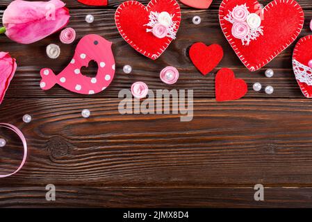 Sewed handmade fabric hearts tulips and ribbon for valentine day on dark wooden background with copy space Stock Photo