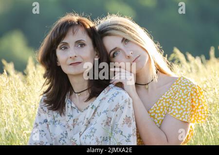 Mature mother with her middle age daughter spending time together outdoors summer time Stock Photo