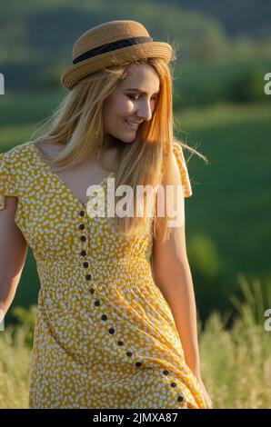 Young blond caucasian female model enjoying outdoor activity at meadow summer evening time Stock Photo