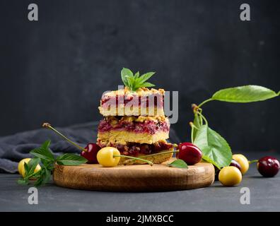 Square slices of cherry crumble lie in a stack on a black board Stock Photo