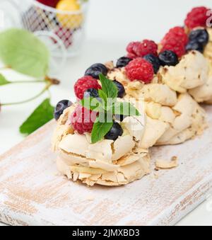 A baked cake made from whipped chicken protein and cream, decorated with fresh berries. Dessert Pavlova Stock Photo
