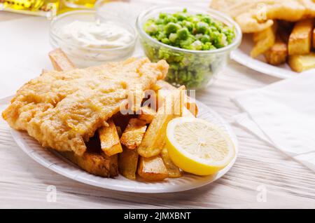 Traditional British street food fish and chips with tartar sauce and mushy peas on paper plate Stock Photo