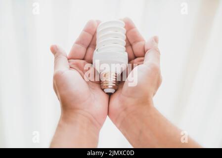 Close up hand holding compact fluorescent light bulb Stock Photo