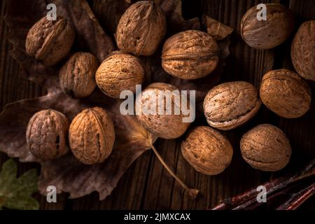 Close up walnuts wooden table with leaves Stock Photo
