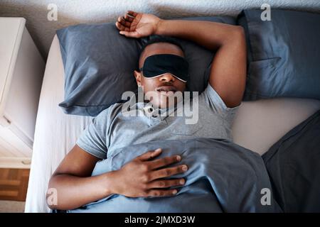 This is what weekends are for. a handsome young man wearing a night mask and sleeping in his bed at home. Stock Photo