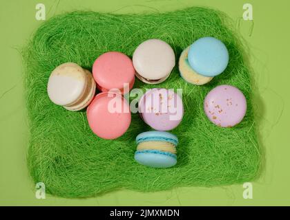 Baked macarons with different flavors on a green background, top view Stock Photo