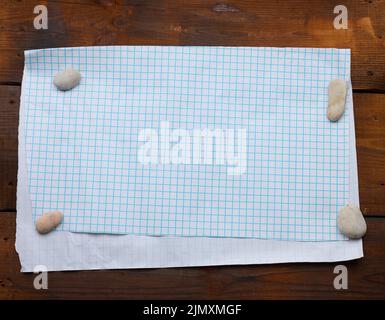 White sheet of paper in a cage on a brown wooden background, place for an inscription Stock Photo