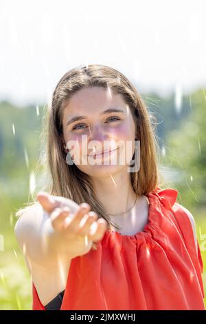 Portrait of happy young woman reaching out to feel the rain while walking by in a countryside rural area. Couple enjoying a hike Stock Photo