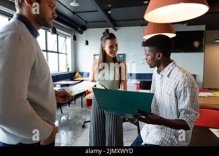 Multiracial colleagues discussing business strategy over file in creative office Stock Photo