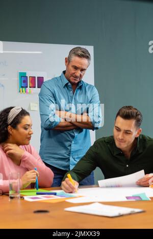Manager looking at multiracial colleagues discussing business strategy in meeting at creative office Stock Photo