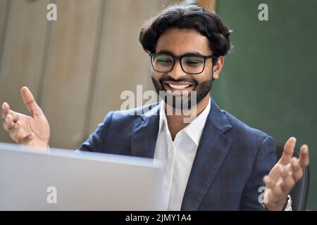 Happy indian business man looking at laptop feeling excited about success. Stock Photo