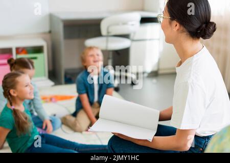 Side view unfocused children paying attention their teacher Stock Photo