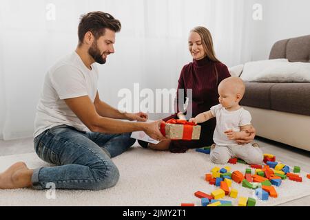 Parents giving gift their baby home Stock Photo