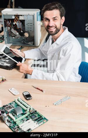 Portrait smiling young male technician holding digital tablet Stock Photo