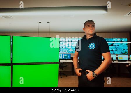 Male security operator working in a data system control room offices Technical Operator Working at workstation with multiple dis Stock Photo