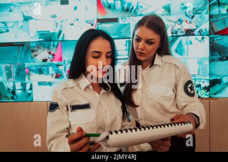 Group of female security operators working in a data system control room Technical Operators Working at workstation with multipl Stock Photo