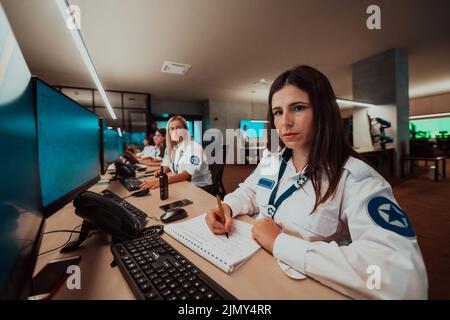 Group of female security operators working in a data system control room Technical Operators Working at workstation with multipl Stock Photo
