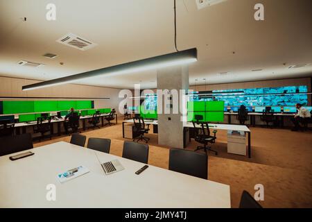 Group of Security data center operators working in a CCTV monitoring room looking on multiple monitors Officers Monitoring Multi Stock Photo