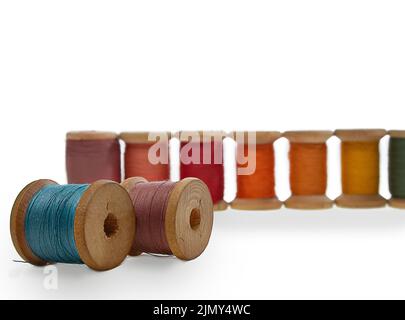 Spools of wooden thread. Blue and lilac lie, red stand in a row. Sewing, repairing clothes. Copy space Stock Photo