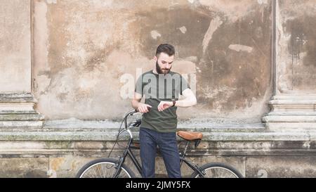 Man with his bicycle looking time wrist watch Stock Photo