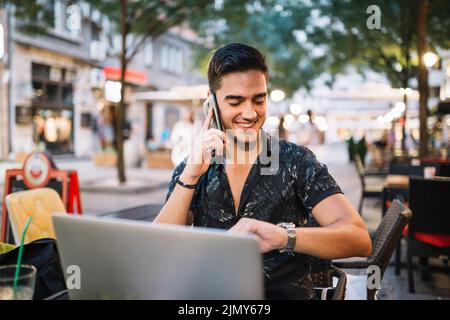 Happy man looking time wrist watch while talking cellphone Stock Photo