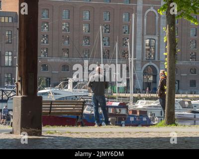 Antwerp, Belgium, April 17, 2022, street fisherman at the Willemdok in Antwerp has a chat with another man Stock Photo