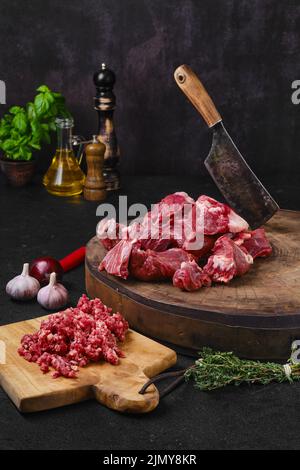 Chopping fresh beef meat for goulash or stew on wooden chopping stump Stock Photo