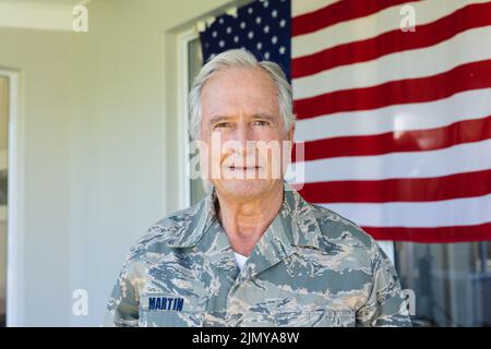 Portrait of caucasian army soldier wearing camouflage clothing standing against flag of america Stock Photo