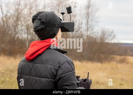 Young man launches rc plane into sky. Teenager with glasses playing with toy radio-controlled airplane outdoors. Boy holding radio remote controller. High quality photo Stock Photo