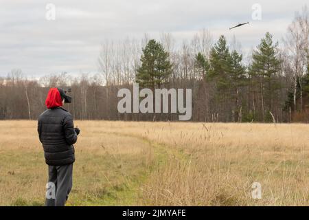 Young man launches rc plane into sky. Teenager with glasses playing with toy radio-controlled airplane outdoors. Boy holding radio remote controller. High quality photo Stock Photo