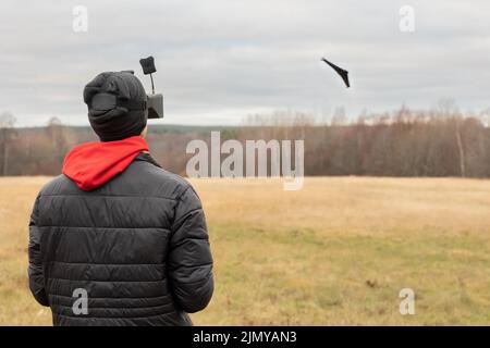 Young man launches rc plane into sky. Teenager with glasses playing with toy radio-controlled airplane outdoors. Boy holding radio remote controller. High quality photo Stock Photo