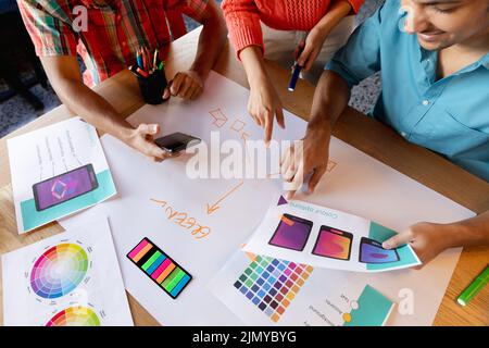 Creative multiracial design professionals discussing over diagrams at table in office Stock Photo