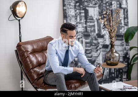 Man happily looking at screen of smartphone Stock Photo