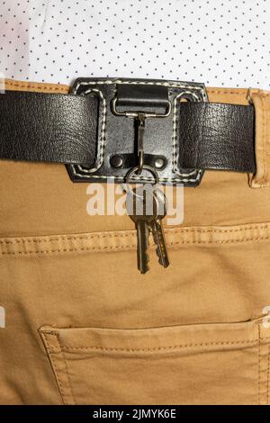 leather key strap with iron carabiner with two keys mounted on a leather belt. Stock Photo