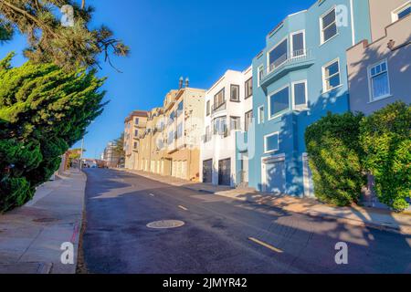 Street with yellow lanes at the front of large residential buildings in San Francisco, California. There are residential buildings on the left with at Stock Photo