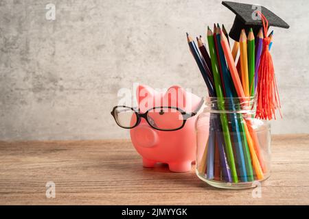 Pigging bank wearing eyeglass with colorful pencils; saving bank education concept. Stock Photo