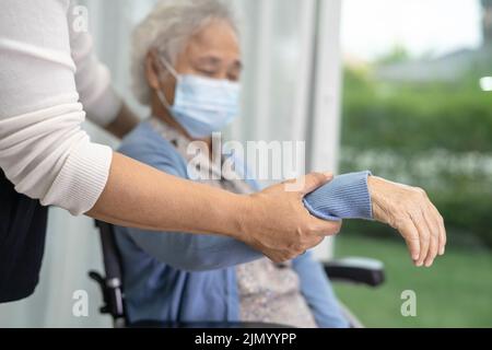 Help Asian senior or elderly old lady woman sitting on wheelchair and wearing a face mask for protect safety infection Covid19 Coronavirus. Stock Photo