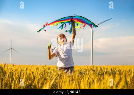 Happy Little girl running in a wheat field with a kite in the summer. Stock Photo