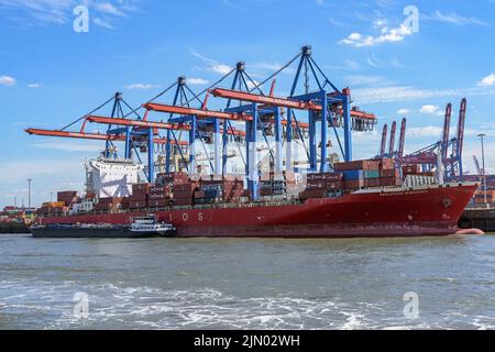 Hamburg, Germany, August 3, 2022: Large container cargo ship is unloaded at the terminal with cranes in the port of Hamburg, concept of transport, shi Stock Photo