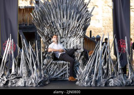 EDITORIAL USE ONLY Reality TV star Sam Thompson sits on the Iron Throne outside the Tower of London to mark the launch of the Game of Thrones prequel, House of the Dragon, airing on Sky and streaming service NOW from August 22. PA PHOTO Picture date: Monday August 8, 2022. The throne is being displayed at the Tower of London today and tomorrow, ahead of the House of the Dragon premiere next week in Leicester Square. Fans and Visitors to the Tower of London will be able to discover more about the news series via a QR code next to the Iron Throne. The Throne will then be touring the country, inc Stock Photo