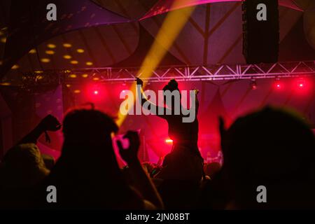 A silhouette of a young woman sitting on her boyfriend's shoulders under pink lights at Latitude Music Festival, Suffolk Stock Photo
