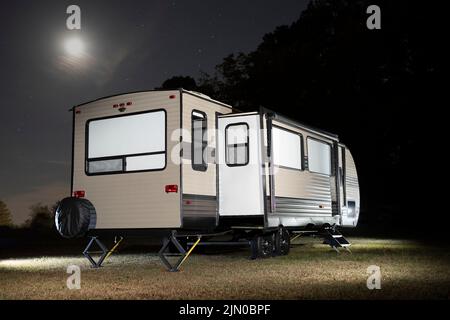 Travel trailer with slides out and moon and stars above Stock Photo